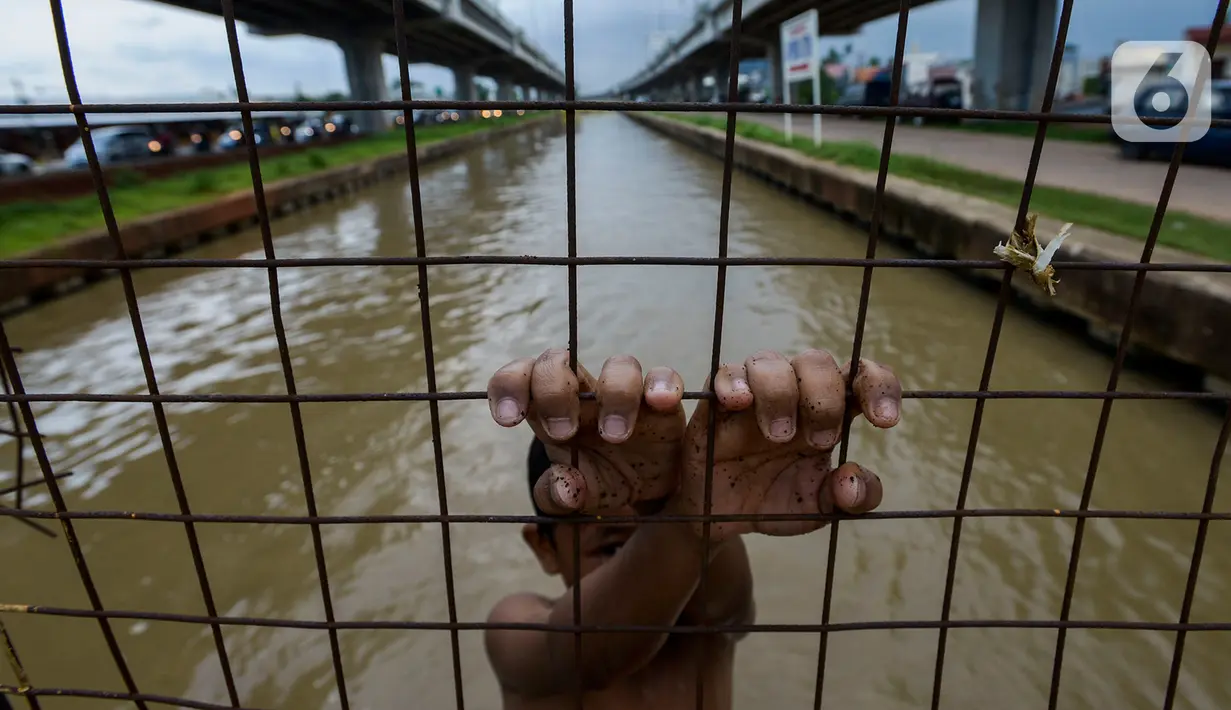 Seorang anak bermain dan berenang di aliran Kalimalang, Jakarta, Sabtu (15/2/2020). Cuaca yang tidak menentu membuat aliran air terkadang menjadi deras sehingga akan membahayakan keselamatan anak-anak saat bermain dan berenang. (merdeka.com/Imam Buhori)