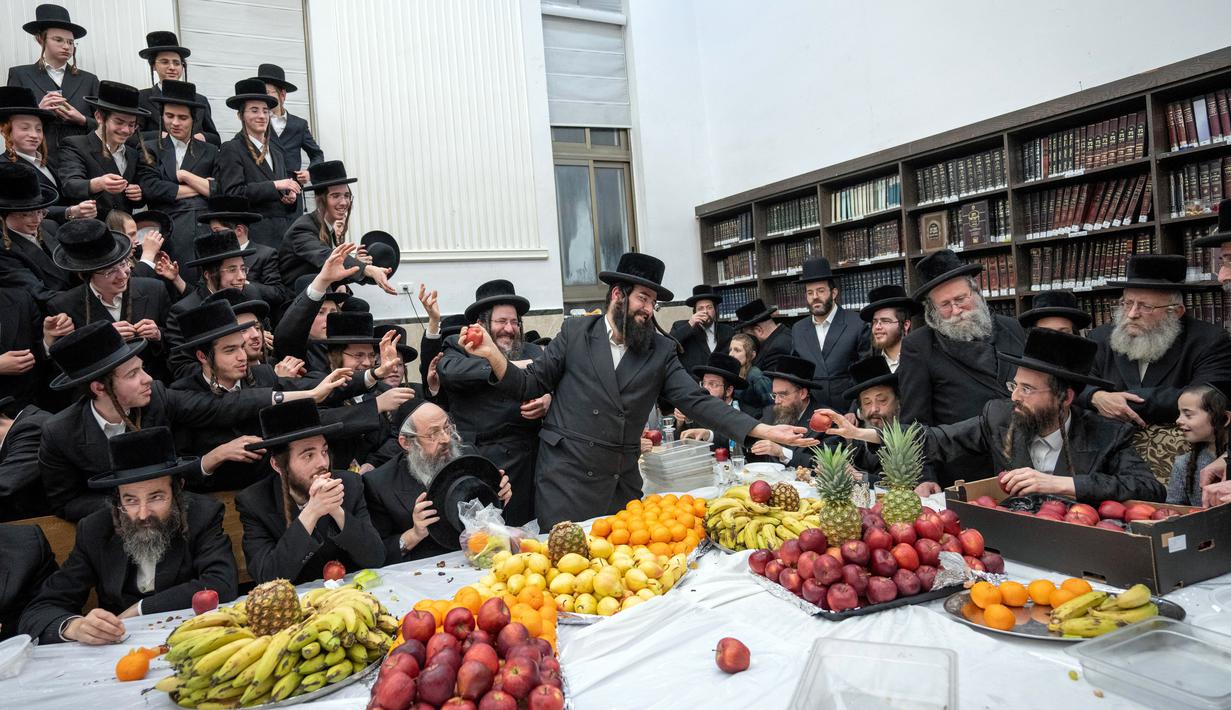 Orang-orang Yahudi Ultra-Ortodoks dari Zweil Hasidim membagikan buah-buahan saat mereka merayakan Hari Raya Tu Bishvat atau Tahun Baru Pohon di Yerusalem, 5 Februari 2023. Saat perayaan Tahun Baru Pohon, orang-orang Yahudi Ultra-Ortodoks berkumpul dengan para rabi mereka di sekitar meja panjang berisi piring-piring berisi beberapa jenis buah-buahan. (AP Photo/Ohad Zwigenberg)