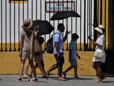 Turis dengan kipas angin dan payung mengunjungi museum arena adu banteng Real Maestranza selama gelombang panas di Seville pada 10 Juli 2023. (AFP/Cristina Quicler)