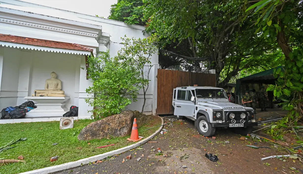 <p>Anggota personel keamanan Sri Lanka berdiri di samping sebuah jip yang rusak di dalam kediaman resmi mantan Perdana Menteri Mahinda Rajapaksa 'Temple Trees', sehari setelah diterobos oleh para pengunjuk rasa di Kolombo pada 10 Mei 2022. PM Sri Lanka Mahinda Rajapaksa mengundurkan diri di tengah gelombang demonstrasi massal yang memprotes cara pemerintah menangani krisis ekonomi. (ISHARA S. KODIKARA / AFP)</p>
