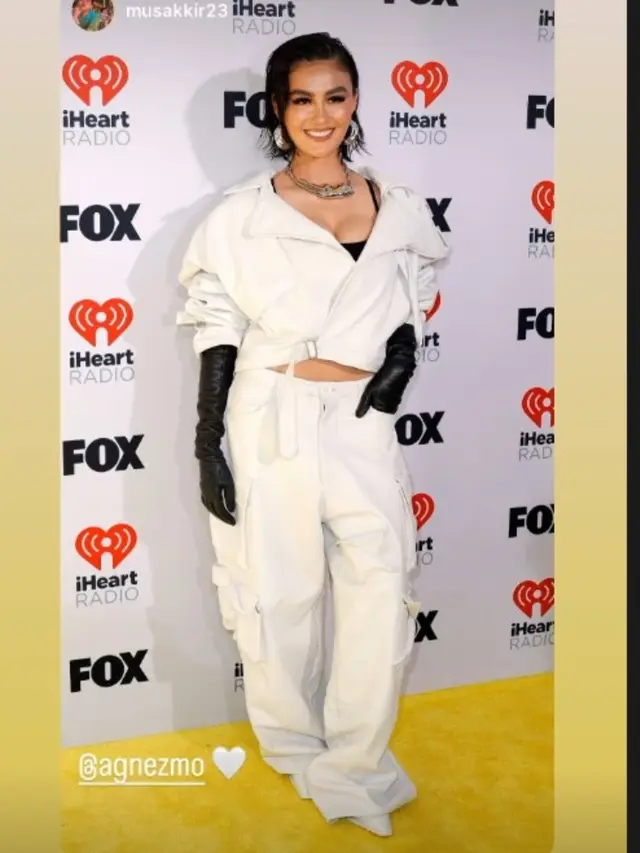 Agnez Mo Bergaya Monokrom dan Tenteng Tas Gucci Berisi Paspor Pacarnya di iHeart Radio Music Awards 2024.