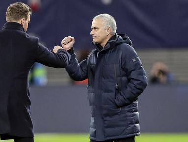 Pelatih Tottenham Hotspur, Jose Mourinho dan pelatih RB Leipzig Julian Nagelsmann menyentuh lengan mereka alih-alih berjabat tangan karena virus corona usai pertandingan leg kedua babak 16 besar Liga Champions di Red Bull Arena, Jerman (10/3/2020). (AP Photo/Michael Sohn)