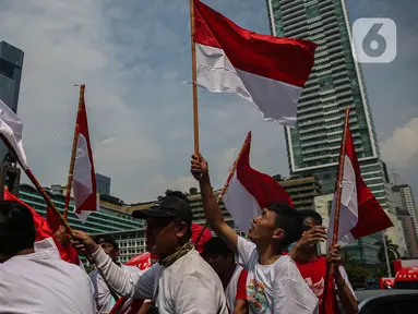 Sejumlah warga yang melintas mengibar-ngibarkan bendera Merah Putih saat melintasi kawasan Bundaran Hotel Indonesia, Jakarta, Sabtu (17/8/2024). (Liputan6.com/Angga Yuniar)