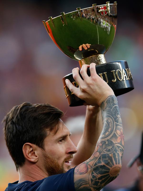 Penyerang Barcelona, Lionel Messi mengangkat Piala Joan Gamper usai pertandingan melawan Boca Juniors di stadion Camp Nou, Spanyol (15/8). Barcelona menang telak 3-0 atas Boca Juniors. (AP Photo/Manu Fernandez)