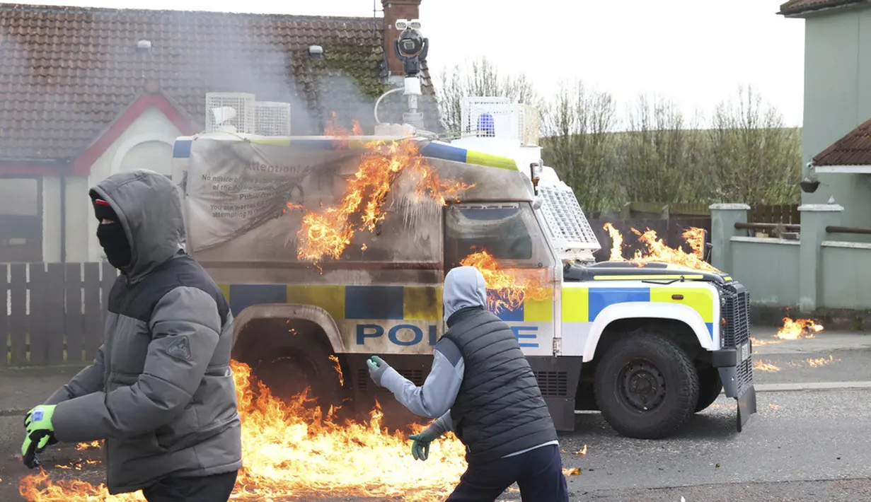 <p>Pemuda bertopeng melemparkan bom molotov ke mobil polisi saat pengunjuk rasa Republikan yang menentang Perjanjian Jumat Agung mengadakan pawai di Londonderry, Irlandia Utara, Senin (10/4/2023). (AP Photo/Peter Morrison)</p>
