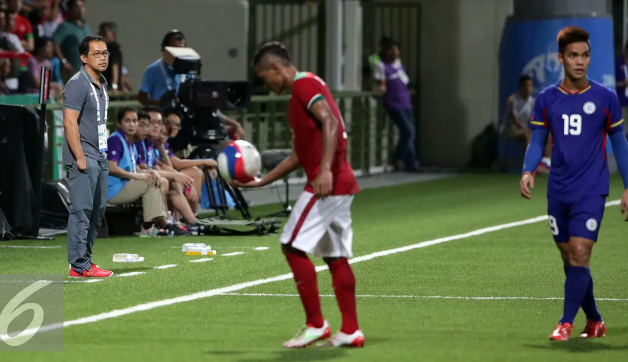 Pelatih timnas Indonesia U-23, Aji Santoso (kiri) memperhatikan laga anak asuhnya melawan Filipina di penyisihan Grup A Sea Games 2015 di Stadion Jalan Besar, Singapura, (9/6/2015). Indonesia unggul 2-0 atas Filipina. (Liputan6.com/Helmi Fithriansyah) 
