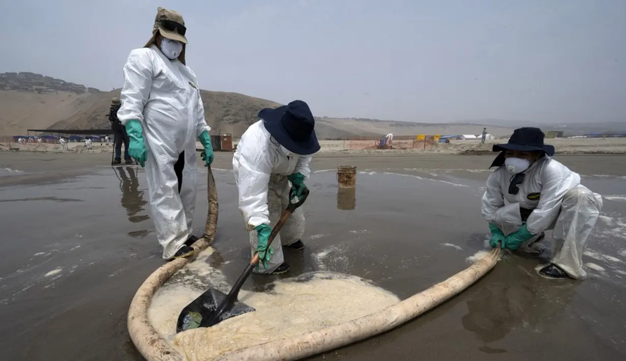 Petugas kebersihan bekerja untuk mengeluarkan minyak dari Pantai Cavero di Callao, Peru, 26 Januari 2022. Pembersihan Pantai Cavero dari tumpahan minyak kapal tanker Mare Doricum yang dihantam gelombang akibat letusan gunung berapi Tonga masih terus dilakukan. (Cris BOURONCLE/AFP)