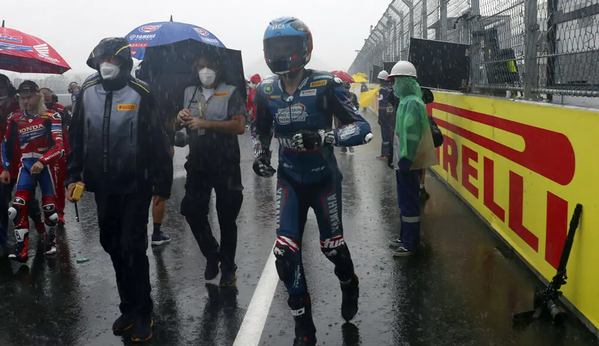 Pembalap dan kru kembali ke paddock saat hujan deras sebelum Race 1 World Superbike (WSBK) di Pertamina Mandalika International Street Circuit, Lombok Tengah, Nusa Tenggara Barat, Sabtu (20/11/2021). Hujan deras memaksa Race 1 WSBK Mandalika ditunda pada 21 November. (AP Photo/Achmad Ibrahim)