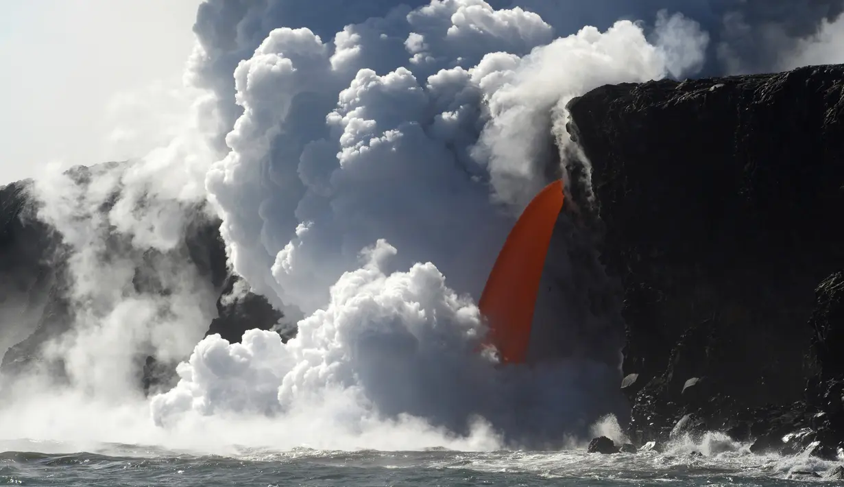 Aliran lava memancar deras dari gunung berapi Kilauea di Hawaii ke Samudra Pasifik, Rabu (1/2). Pertunjukkan alam tersebut menciptakan air terjun lava. (Shane Turpin / Lava Ocean Tours via AP)