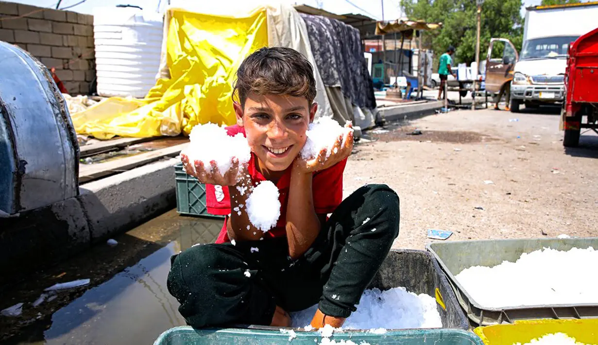 Seorang pedagang kaki lima mendinginkan diri dengan es yang ia jual untuk mengatasi cuaca panas yang mencapai 123,8 F (51 C) di Basra, Irak, Kamis (1/7/2021). Pemerintah Irak menetapkan 1 Juli 2021 sebagai hari libur resmi di Baghdad karena gelombang panas yang menyengat. (AP Photo/Nabil al-Jurani)