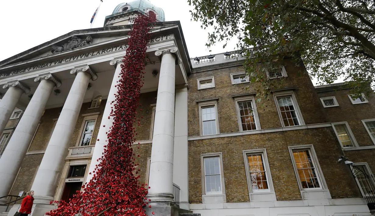 Anna Wigley mendongak ke arah karya seni bunga poppy bertajuk 'Weeping Window' di The Imperial War Museum, London, Kamis (4/10). Musuem tersebut tampak seperti berdarah dengan pajangan karya seni bunga poppy. (AP Photo/Kirsty Wigglesworth)