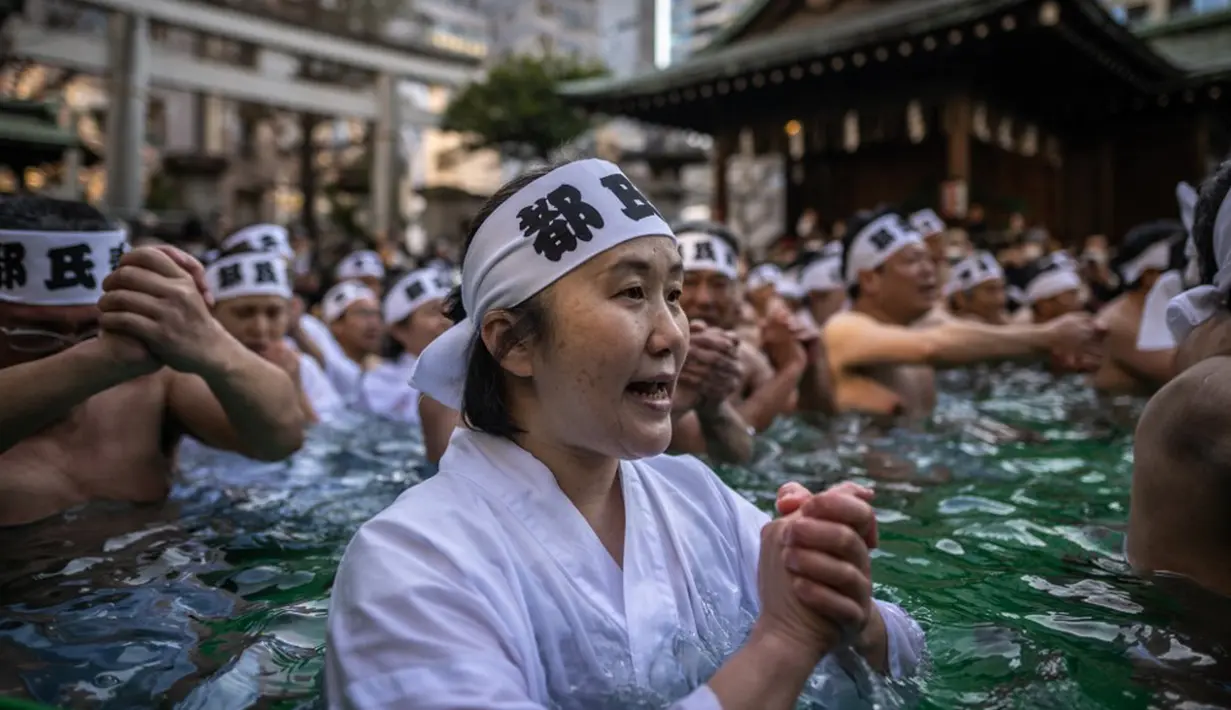Penganut Shinto mandi dengan air dingin di Kuil Teppozu Inari, Tokyo, Jepang, 8 Januari 2023. Ritual Tahun Baru ini dilakukan untuk memurnikan jiwa dan raga. (Philip FONG/AFP)