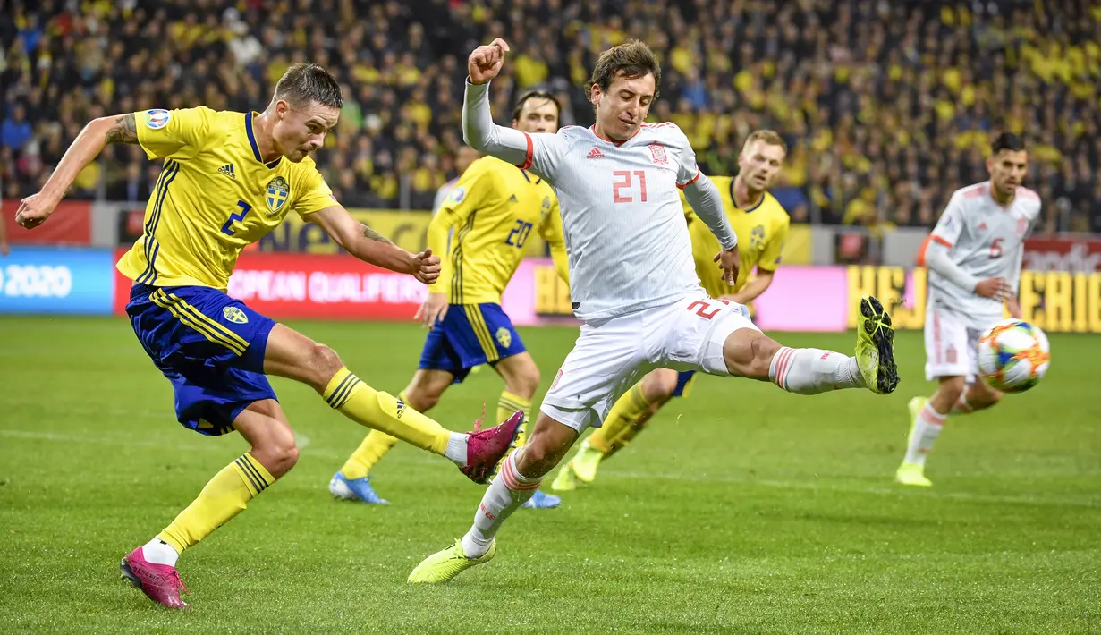 Pemain Swedia, Mikael Lustig mengumpan bola dari kawalan pemain Spanyol, Mikel Oyarzabal pada pertandingan Grup F Piala Eropa 2020 di Friends Arena di Stockholm (15/10/2019). Spanyol bermain imbang 1-1 dan memastikan diri lolos ke putaran final Piala Eropa 2020. (Anders Wiklund/TT via AP)