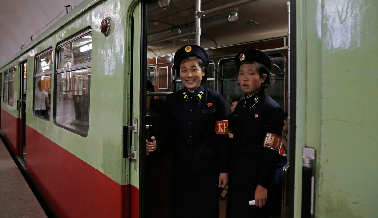 Dua petugas berdiri di pintu kereta yang tengah berhenti di stasiun kereta bawah tanah di Pyongyang, 13 September 2018. Untuk interior gerbong, kereta menampilkan interior kayu. (AP Photo/Kin Cheung)