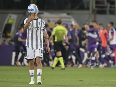 Penyerang Juventus, Paulo Dybala memegang bola saat para pemain Fiorentina melakukan selebrasi selama pertandingan lanjutan Liga Serie A Italia di Florence, Italia, Minggu (22/5/2022). Fiorentina menang atas Juventus dengan skor 2-0. (Alfredo Falcone/LaPresse via AP)