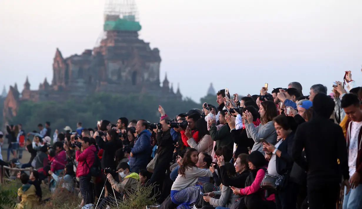 Wisatawan lokal dan asing mengunjungi kuil tua Myanmar sesaat sebelum matahari terbit di Bagan, distrik Nyaung U, Myanmar tengah (16/12). Banyak wisatawan menggunakan balon udara untuk menikmati pemandangan langit Bagan. (AP Photo/Aung Shine Oo)