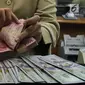 Teller tengah menghitung mata uang rupiah di penukaran uang di Jakarta, Junat (23/11). Nilai tukar dolar AS terpantau terus melemah terhadap rupiah hingga ke level Rp 14.504. (Liputan6.com/Angga Yuniar)