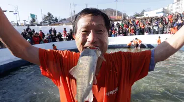 Seorang peserta berpose dengan ikan dengan saat acara Festival Es di sungai Hwacheon yang membeku di Korea Selatan, Sabtu (14/1). (AP Photo/Ahn Young-joon)