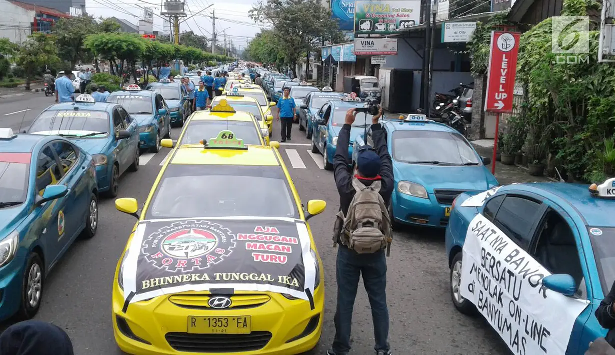 Ratusan taksi dan angkutan umum gelar aksi mogok tolak transportasi online di alun-alun Kota Purwokerto, Selasa (17/10). Mereka mengeluhkan pendapatan yang menurun sejak keberadaan transportasi online. (Liputan6.com/Pool/ Dimas dan Neto Adrianto)