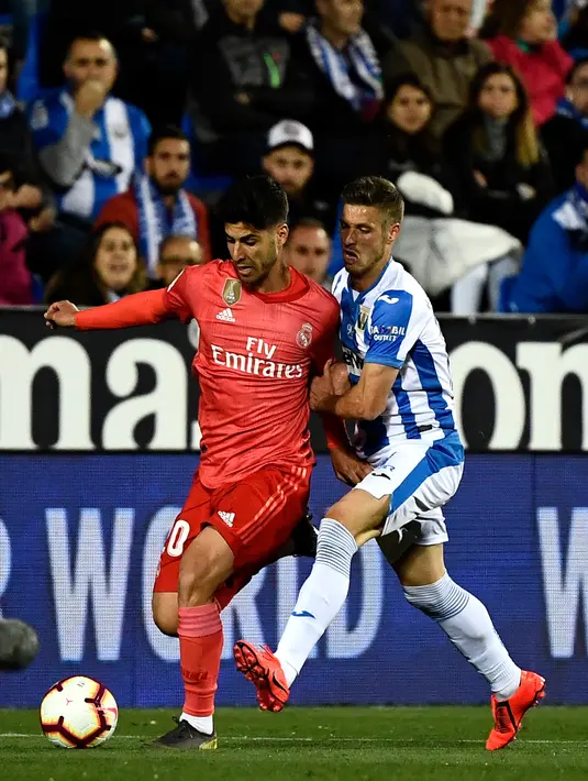 Gelandang Real Madrid, Marco Asensio berebut bola dengan gelandang Leganes, Ruben Perez dalam lanjutan La Liga 2018-2019 di Estadio Municipal Butarque, Senin (15/4). Real Madrid hanya mampu meraih hasil imbang 1-1 saat bertandang ke markas Leganes. (PIERRE-PHILIPPE MARCOU / AFP)