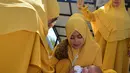Tokoh adat dan agama menggendong bayi pada ritual 'peutron tanoh aneuk' (turun tanah anak) di Banda Aceh, Aceh, Senin (15/7/2019). Ritual turun tanah anak yang telah menjadi tradisi sakral bagi masyarakat Aceh yang dilaksanakan pada saat bayi berusia 44 hari. (CHAIDEER MAHYUDDIN / AFP)