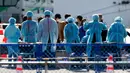 Petugas memeriksa penumpang yang turun dari kapal pesiar Diamond Princess yang dikarantina di Yokohama, Jepang, Jumat (21/2/2020). Dua orang Jepang dari kapal pesiar Diamond Princess dilaporkan meninggal dunia. (AP Photo/Eugene Hoshiko)
