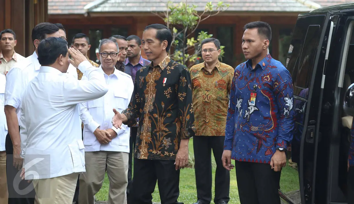 Presiden Joko Widodo (Jokowi) mengulurkan tangan sementara Ketua Umum Partai Gerindra Prabowo Subianto melakukan sikap hormat saat menyambut kedatangan Presiden dan rombongan di kediamannya di Hambalang, Bogor, Senin (31/10). (Liputan6.com/Faizal Fanani)