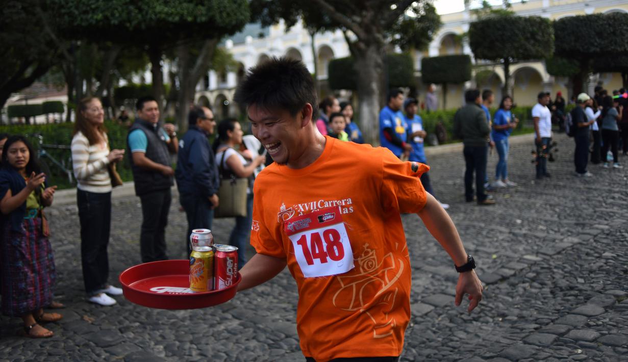Seorang pramusaji beradu kecepatan sambil membawa nampan dalam Waiters Race ke-16 di Antigua, barat daya Ibu Kota Guatemala City, Rabu (14/11). Lomba ini diikuti oleh ratusan peserta yang merupakan pelayan restoran dan kafe setempat. (JOHAN ORDONEZ/AFP)