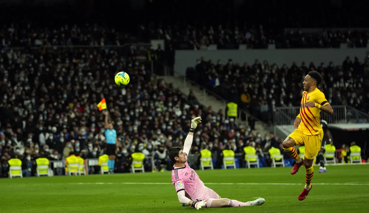 Pemain Barcelona Pierre-Emerick Aubameyang (kanan) mencetak gol ke gawang Real Madrid yang dijaga kiper Thibaut Courtois pada pertandingan sepak bola La Liga Spanyol di Stadion Santiago Bernabeu, Madrid, Spanyol, Minggu (20/3/2022). Barcelona menang 4-0. (AP Photo/Manu Fernandez)
