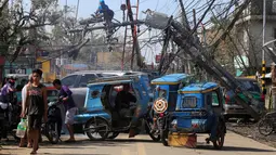Pekerja memperbaiki tiang listrik yang roboh setelah dihantam Topan Nock-ten di Kota Iriga Camarines Sur, Filipina tengah (27/12). Topan Nock-Ten dilaporkan memutus listrik di lima provinsi saat puncak perayaan Natal. (REUTERS/Romeo Ranoco)