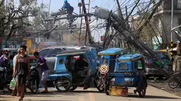 Pekerja memperbaiki tiang listrik yang roboh setelah dihantam Topan Nock-ten di Kota Iriga Camarines Sur, Filipina tengah (27/12). Topan Nock-Ten dilaporkan memutus listrik di lima provinsi saat puncak perayaan Natal. (REUTERS/Romeo Ranoco)