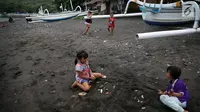 Anak-anak bermain pasir di kawasan wisata Pantai Amed, Bali, Selasa (5/12). Erupsi Gunung Agung membuat sektor pariwisata di Pulau Dewata, terutama wilayah Amed sepi dari wisatawan, baik lokal maupun mancanegara. (Liputan6.com/Immanuel Antonius)