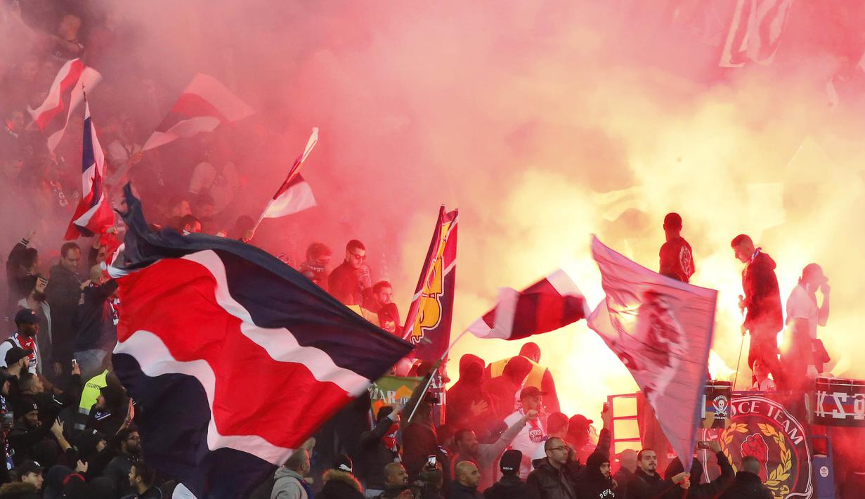 Para suporter PSG menyalakan flare merayakan kemenangan atas Nice pada laga Ligue 1 Prancis di Stadion Parc des Princes, Paris, Jumat (27/10/2017). PSG menang 3-0 atas Nice. (AFP/Michel Euler)