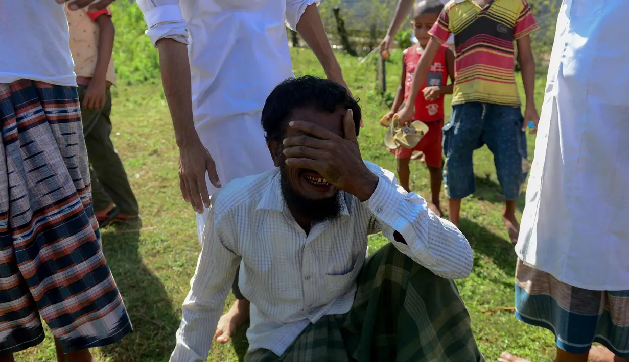 Pengungsi Rohingya Alif Jukhar (tengah) menangis setelah menguburkan kedua orang tuanya yang meninggal saat kapal mereka terbalik untuk menyeberangi Myanmar ke Bangladesh di sebuah pemakaman di Sha Porir Dwip, Teknaf (9/10). (AFP Photo/Munir Uz Zaman)