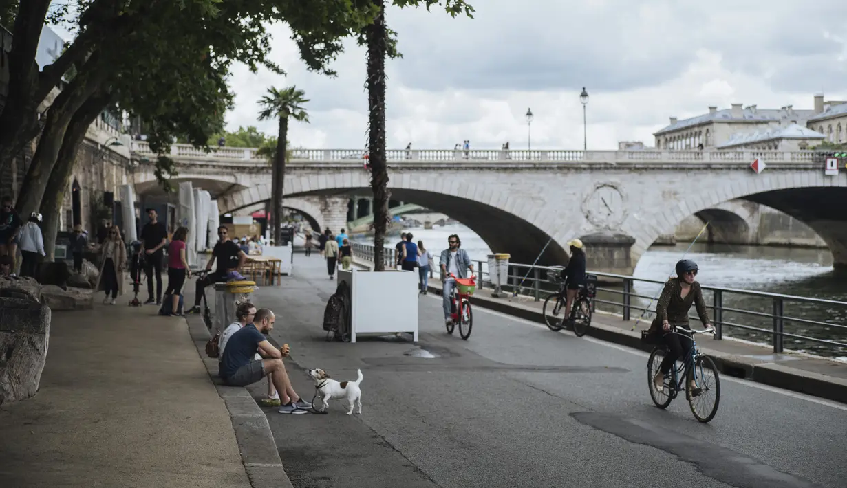 Orang-orang menikmati tepian Sungai Seine di Paris, Prancis, Minggu (11/7/2021). Prancis telah mengakhiri kewajiban mengenakan masker di luar ruangan dan pencabutan jam malam sejak pertengahan Juni lalu menyusul penurunan kasus COVID-19. (AP Photo/Lewis Joly)