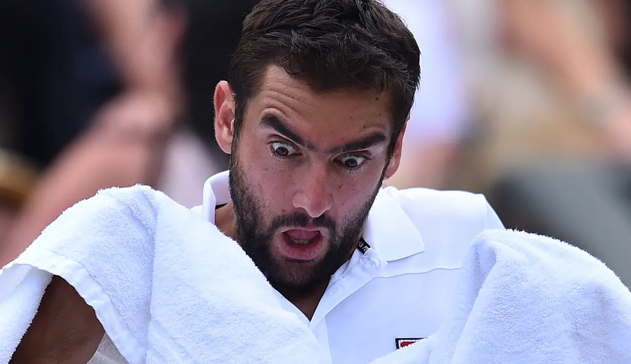 Mimik wajah Marin Cilic saat menggunakan handuk pada perempat final melawan Gilles Muller di The All England Lawn Tennis Club, London, (11/7/2017). (AFP/Glyn Kirk)