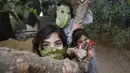 Tiga anak Palestina berpose dengan masker yang terbuat dari kubis di halaman rumahnya di Beit Lahia di Jalur Gaza utara (16/4/2020).  (AFP/Mohamed Abed)