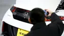 Pengunjung mengambil gambar bagian belakang mobil Honda S660 di markas besar Honda Motor Co di Tokyo, Jepang, (24/2). Mobil berbobot kira-kira 830kg dengan transmisi manual dan 850kg dengan CVT otomatis. (REUTERS/Thomas Peter)