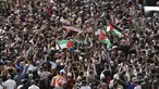 Orang-orang Palestina mengibarkan bendera nasional saat membawa peti mati jurnalis Al-Jazeera Shireen Abu Akleh yang tewas tertembak selama prosesi pemakamannya di dekat Gerbang Jaffa, salah satu gerbang utama Kota Tua Yerusalem, 13 Mei 2022. Shireen Abu Akleh yang merupakan jurnalis senior berusia 51 tahun itu terkena tembakan di kepala ketika meliput serangan Israel di Kota Jenin, di wilayah Tepi Barat yang diduduki pada 11 Mei 2022 lalu. (Ahmad GHARABLI / AFP)