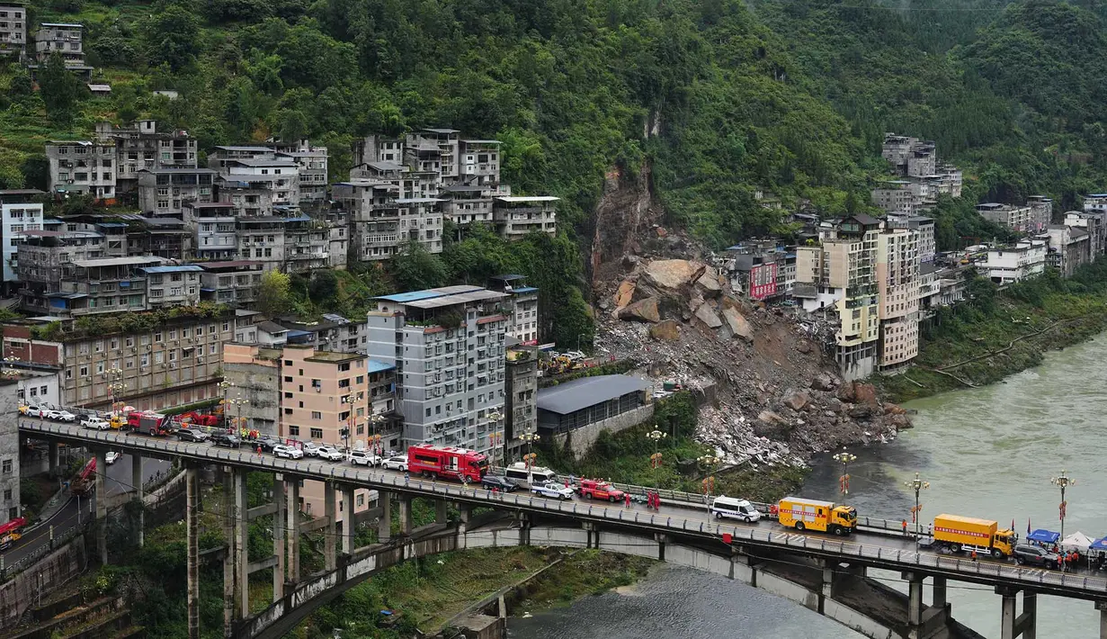 Kendaraan penyelamat bersiaga di jembatan saat tim penyelamat melakukan operasi pencarian dan penyelamatan di lokasi tanah longsor di Kabupaten Pengshui, Chongqing, Tiongkok barat daya, Sabtu, 18 Juli 2026. (AP Photo/Andy Wong)