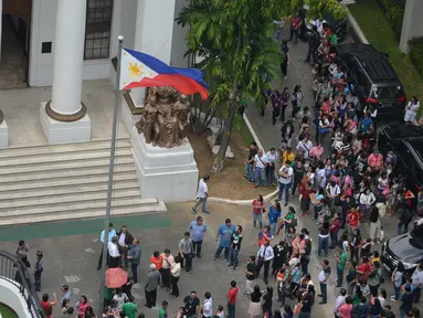 Pegawai pengadilan berkumpul di depan gedung setelah gempa melanda Manila, Filipina (11/8). Gempa bertenaga 6,2 skala Richter mengguncang wilayah selatan ibukota Filipina yang menyebabkan bangunan di Manila rusak. (AFP Photo/Ted Aljibe)