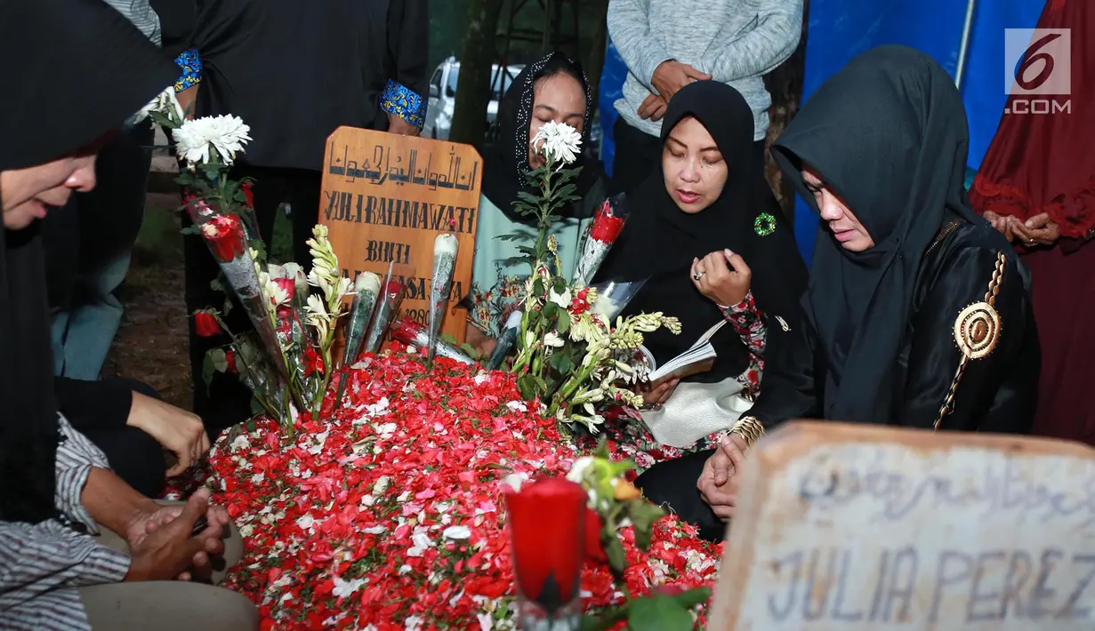 Kesedihan Ibu Julia Perez, Sri Wulansih saat sedang mendoakan di makam Julia Perez di TPU Pondok Ranggon, Jakarta, Selasa (13/6). Setelah mendoakan, Sri Wulansih beserta keluarga menaburkan bunga di makam Jupe. (Liputan6.com/Herman Zakharia)