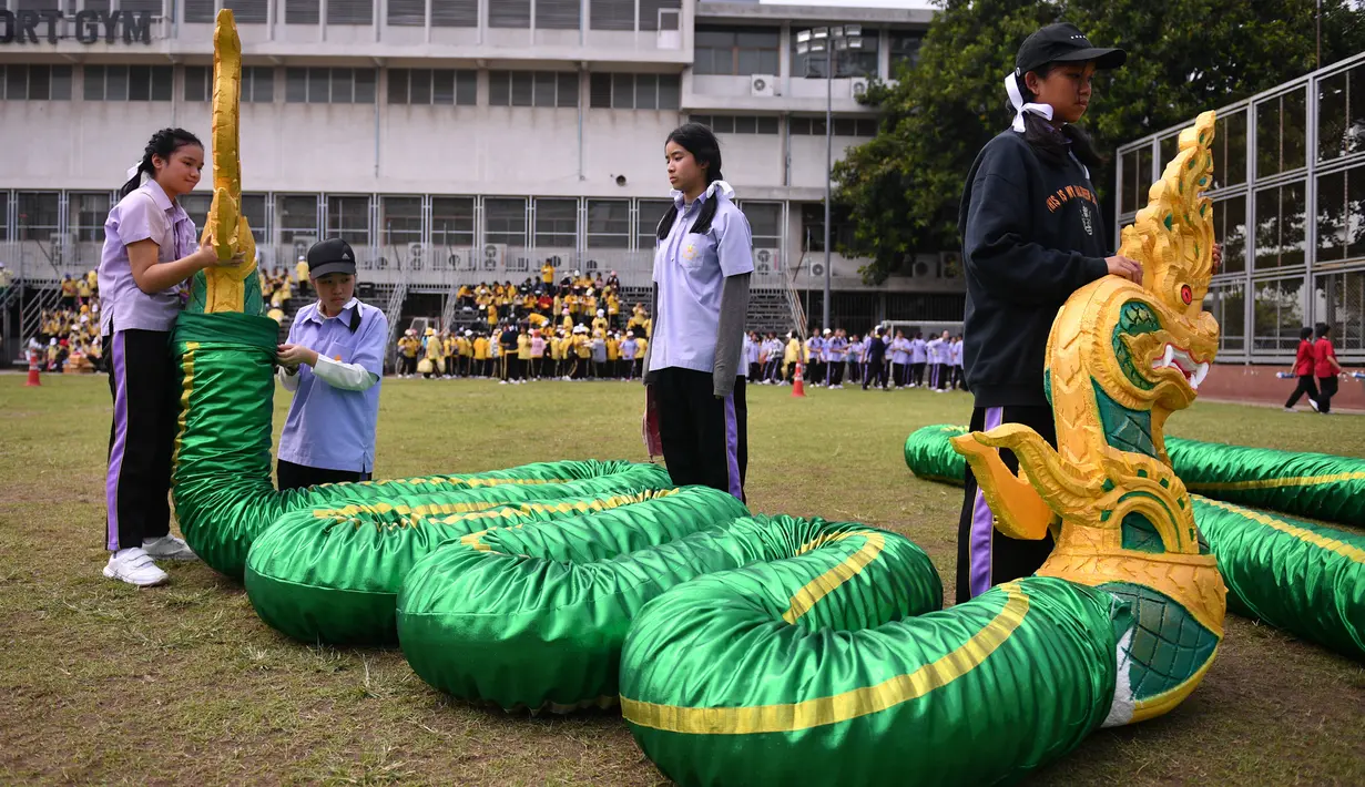 Para pelajar mempersiapkan naga saat mengikuti gladi resik di halaman sekolah di Bangkok, Thailand (13/11/2019). Gladi resik diadakan sebagai persiapan untuk kunjungan Paus Fransiskus yang  akan berada di Thailand pada 20-23 November 2019. (AFP Photo/Chalinee Thirasupa)