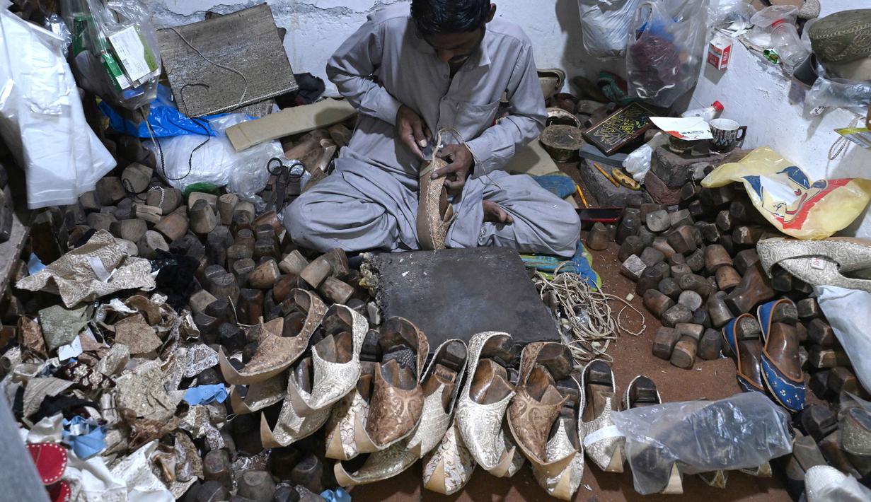 Para perajin terlihat sibuk membuat pesanan sepatu khas Pakistan, Khussa. Tampak dalam foto, aktivitas para perajin sepatu membuat sandal di sebuah bengkel menjelang perayaan Idul Fitri selama bulan suci Ramadhan 1447 Hijriah di Lahore pada 14 Maret 2026. (Arif ALI/AFP)