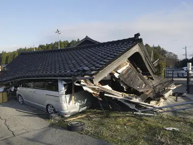 Sebuah kendaraan berada di bawah sebuah bangunan yang runtuh akibat gempa bumi di Shikamachi, prefektur Ishikawa, Jepang, Selasa (2/1/2024). (Kyodo News via AP)