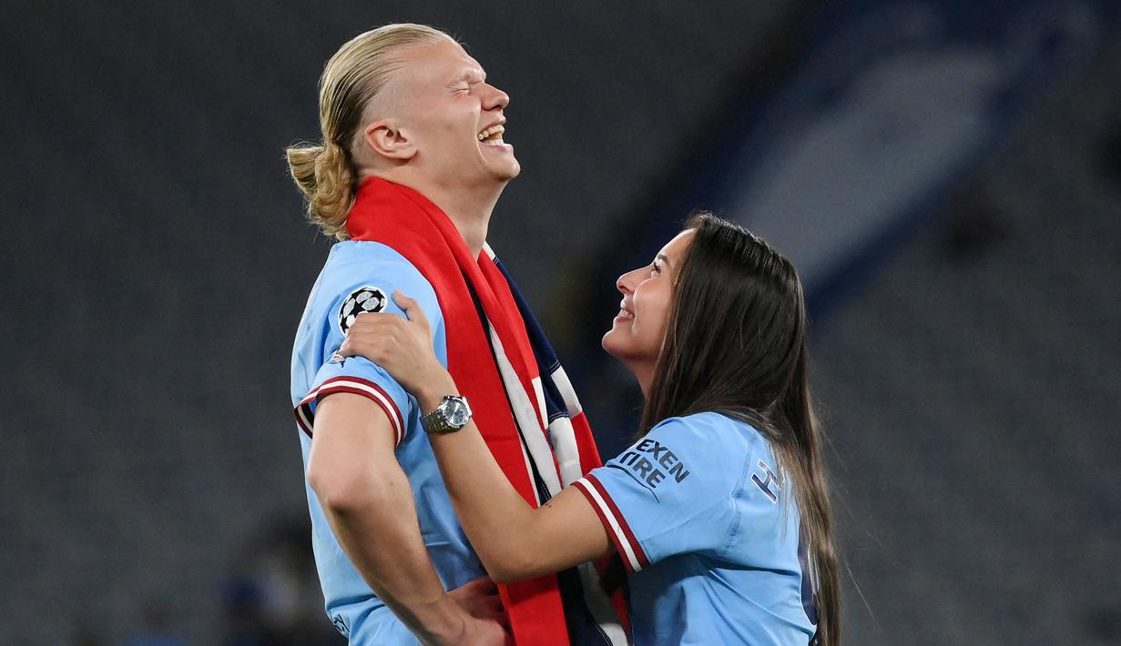 Pemain Manchester City, Erling Haaland, bercanda dengan kekasihnya Isabel Haugseng Johansen saat perayaan gelar juara Liga Champions di Ataturk Olympic Stadium, Istanbul, Minggu (11/6/2023). Erling Haaland tampil luar biasa dan mampu meraih treble winner di musim perdananya bersama City. (AFP/Franck Fife)