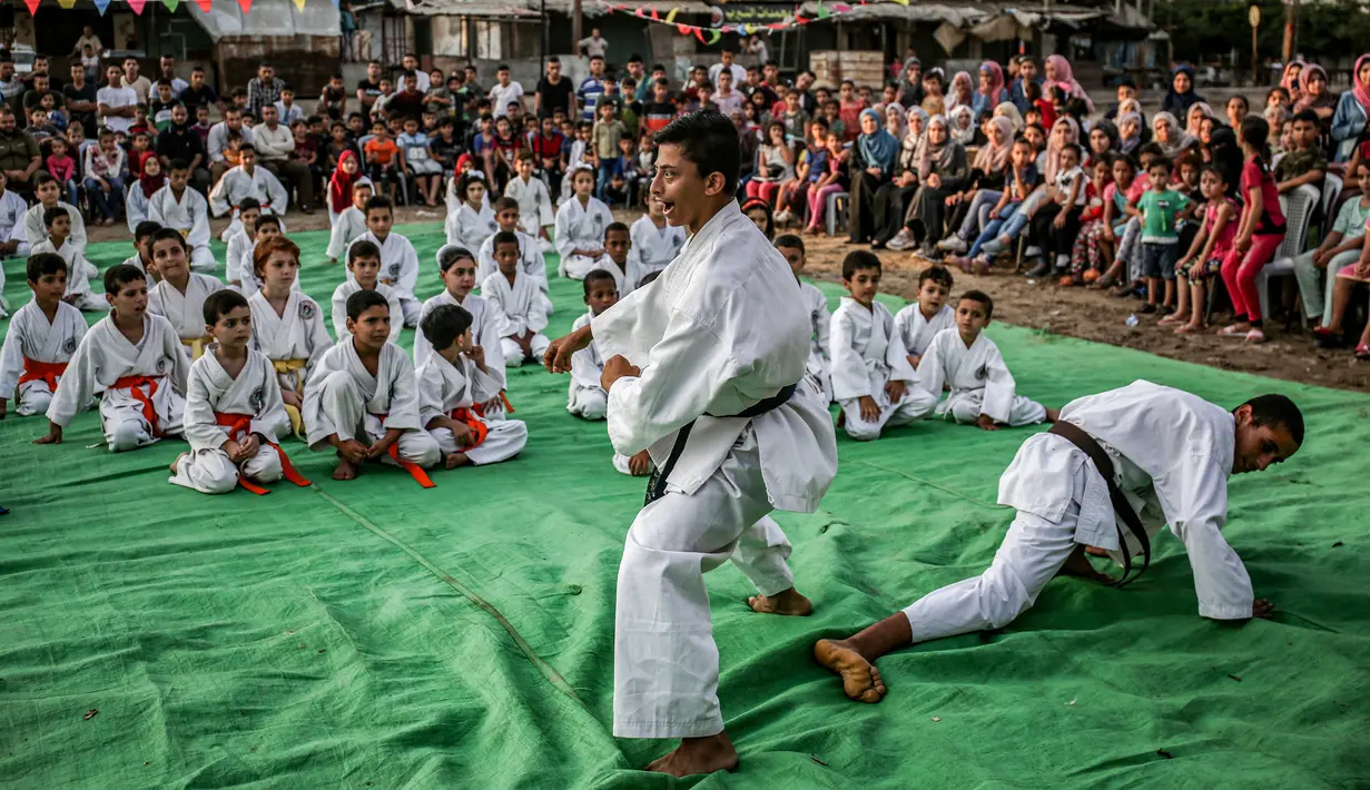 Anak-anak menyaksikan para pelatih bertarung selama upacara promosi Karate di pusat olahraga di kamp Rafah untuk para pengungsi Palestina di Jalur Gaza selatan (20/9/2019). (AFP Photo/Said Khatib)