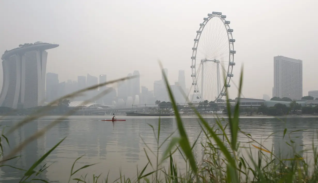 Seorang pria menggunakan kayak melewati langit Singapura yang diselimuti kabut, Senin (5/10). Indeks Standar Polutan (PSI) kabut asap mencapai angka tertinggi 186 pada jam 4 sore waktu setempat, menurut Badan Lingkungan Nasional. (REUTERS/Edgar Su)