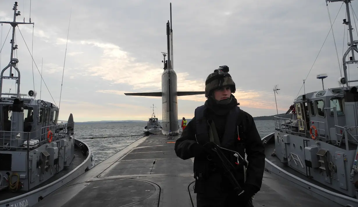 Prajurit angkatan laut bersenjata lengkap memeriksa bagian dek kapal selam yang dikawal oleh dua kapal tunda, Brest, Perancis (21/10). Kapal selam Perancis yang bernama "Le Vigilant" ini diisi oleh 110 orang. (AFP /Valérie Leroux )