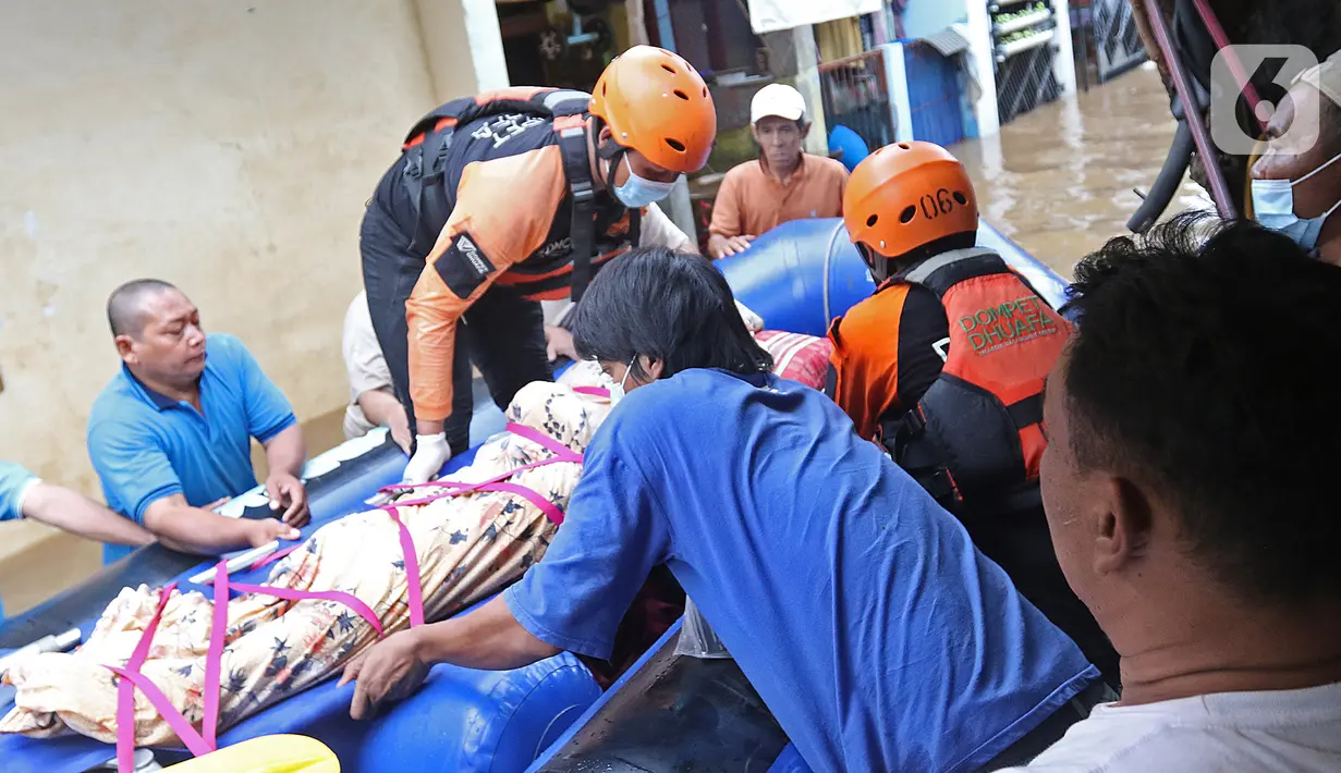 Relawan dan keluarga menaikkan jenazah warga lansia ke atas perahu karet saat banjir di Cipinang Melayu, Jakarta Timur, Jumat (19/2/2021). Seorang nenek (80) meninggal di kediamannya, di lokasi banjir, di RW 04, kawasan tersebut karena sakit dan sudah lanjut usia. (Liputan6.com/Herman Zakharia)